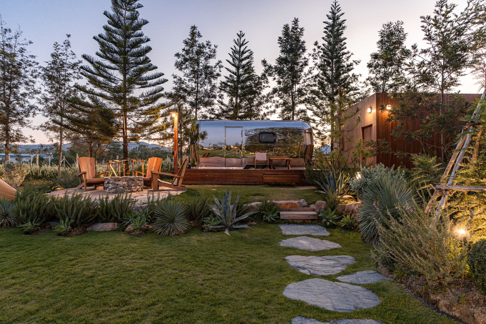 Silver Camper Van and stone garden at dusk surrounded by pines