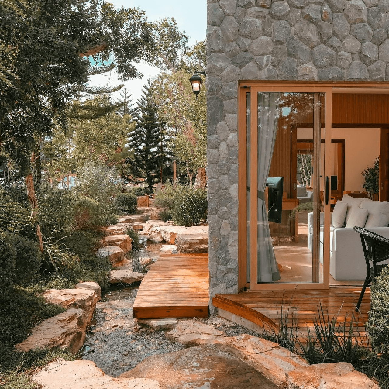Stone-clad villa beside a natural stream with wooden bridge