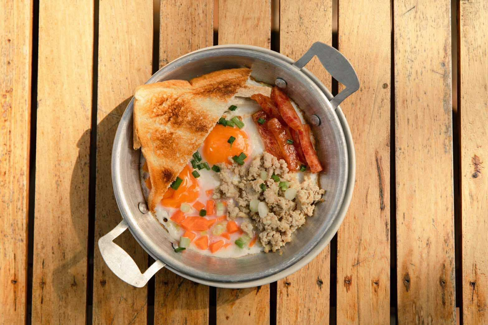 Top-down skillet eggs with sausage and ground pork on wooden deck